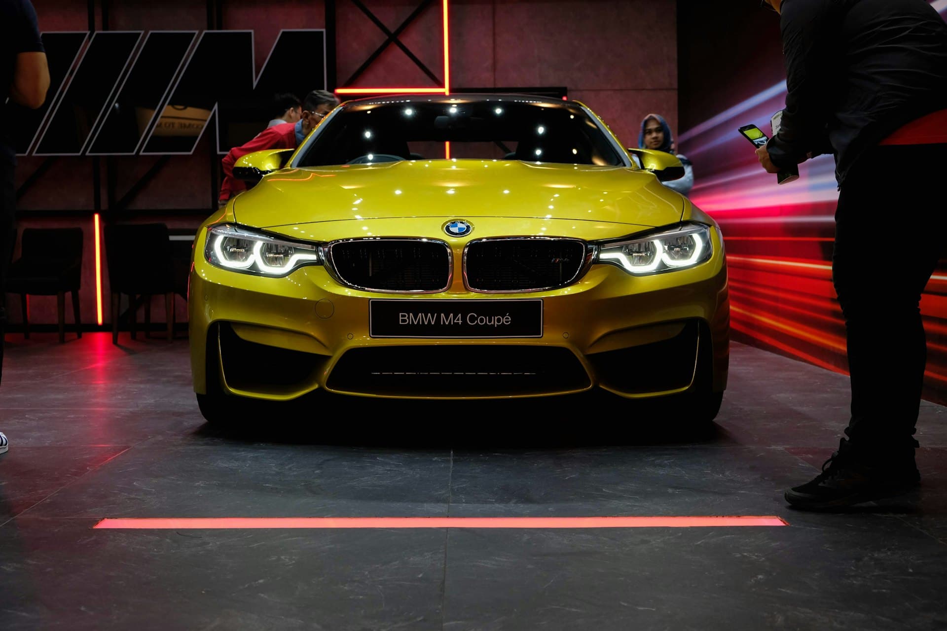 A coupe with a specialty wrap finish lit under dark studio lighting.