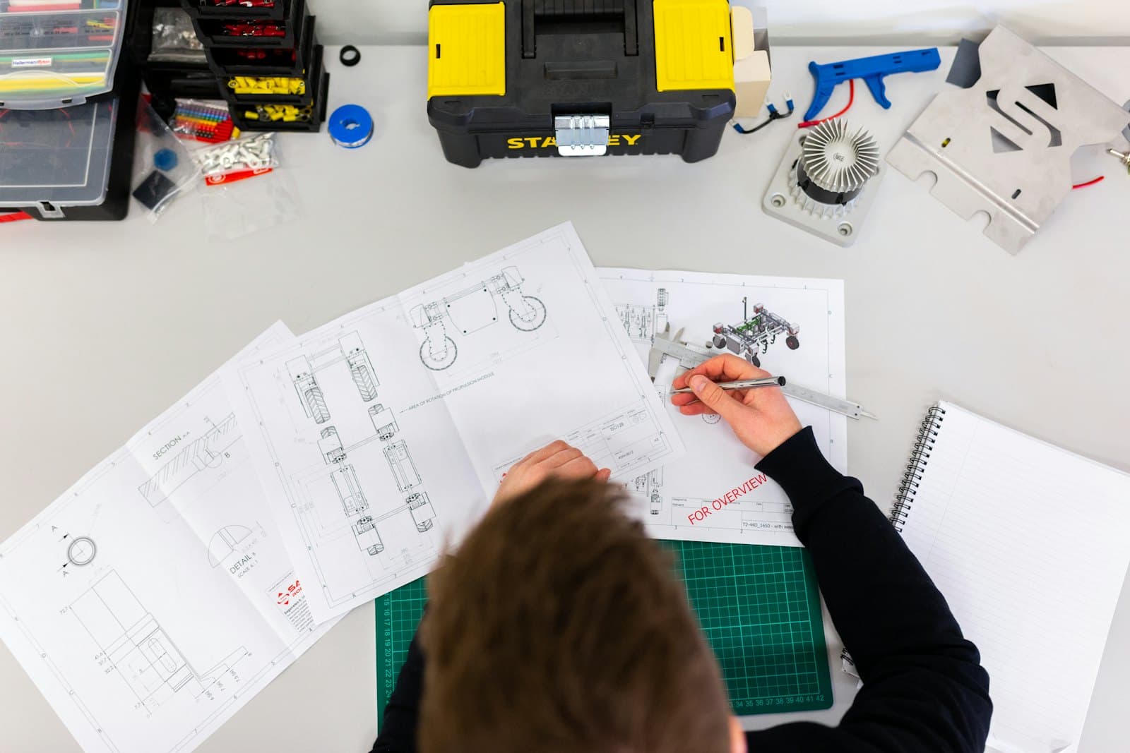 A flat-lay of technical drawings, calipers, and tools used to plan a job.