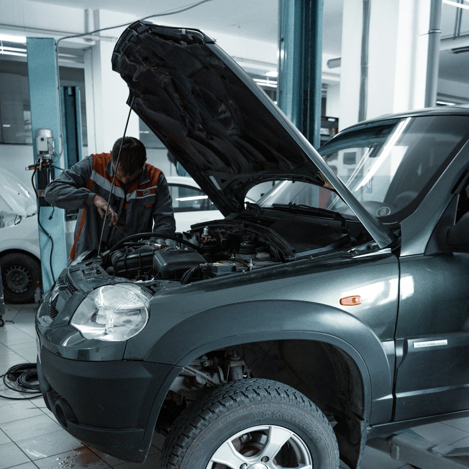 An installer working on a vehicle in a controlled, cool-lit service bay.