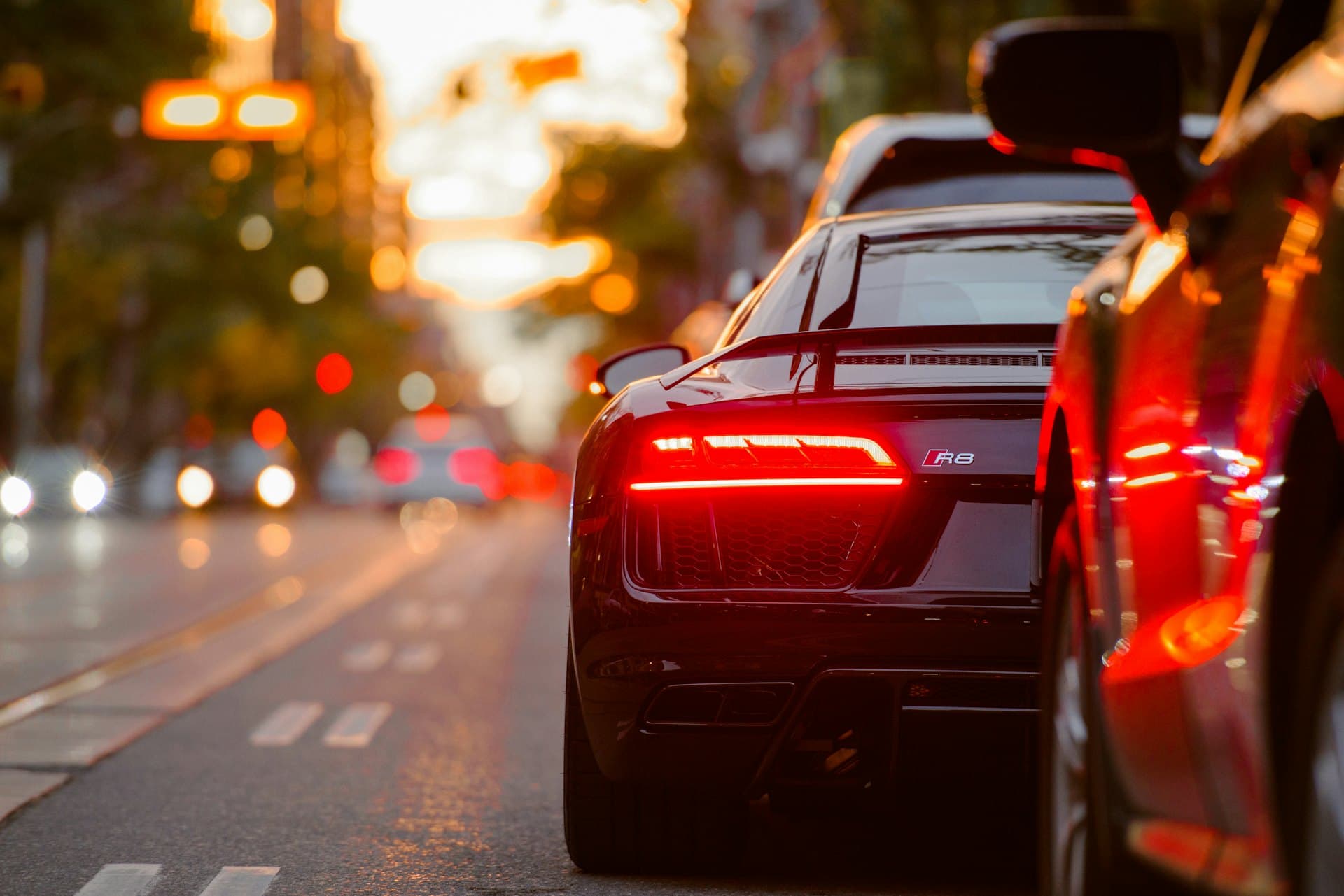 A black mid-engine coupe photographed at night with glowing rear lights, paint protected to a deep gloss.