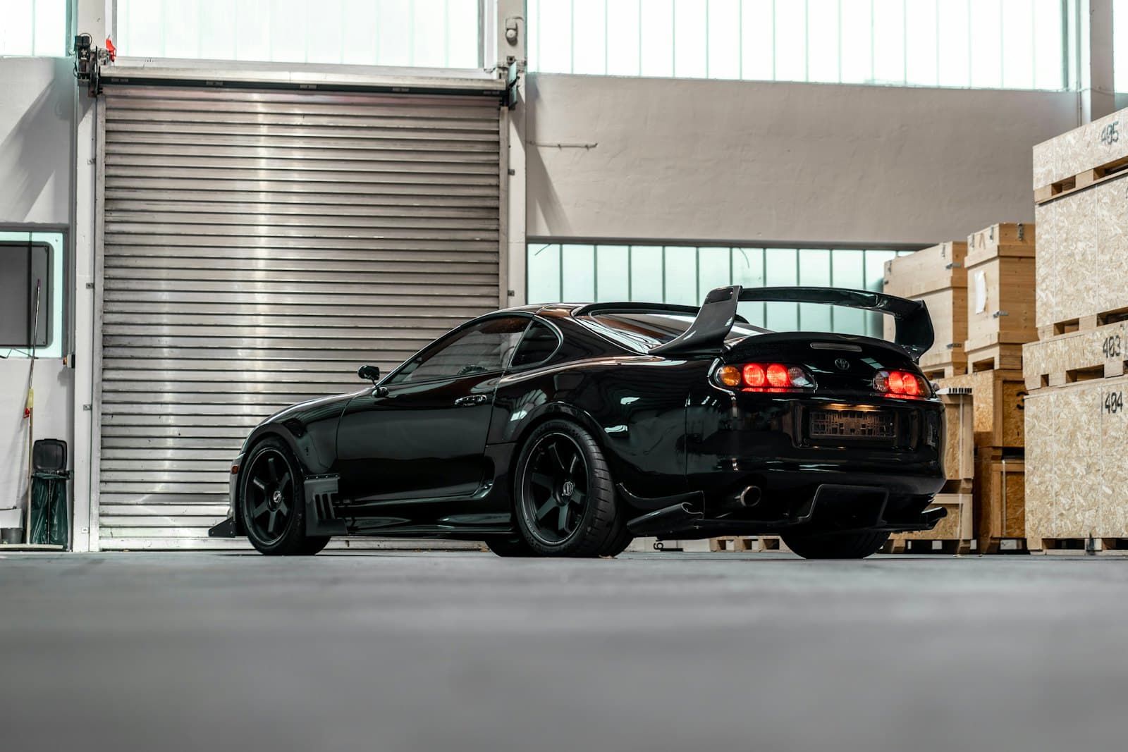 A black sports car in a warehouse with dark rear-glass tint.